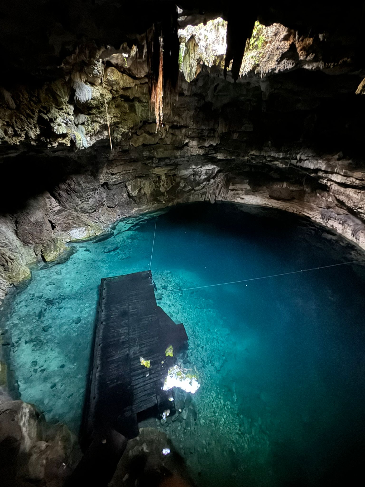 Fotografía de cueva con laguna y muelle en su interior